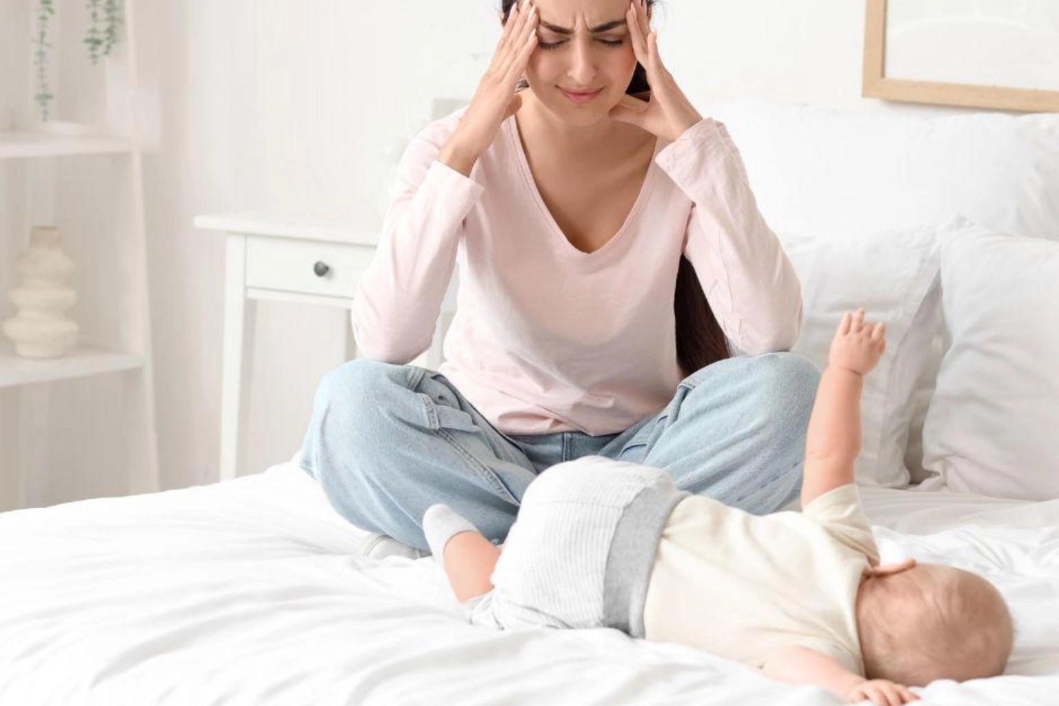 Stressed out mom sitting on bed with newborn